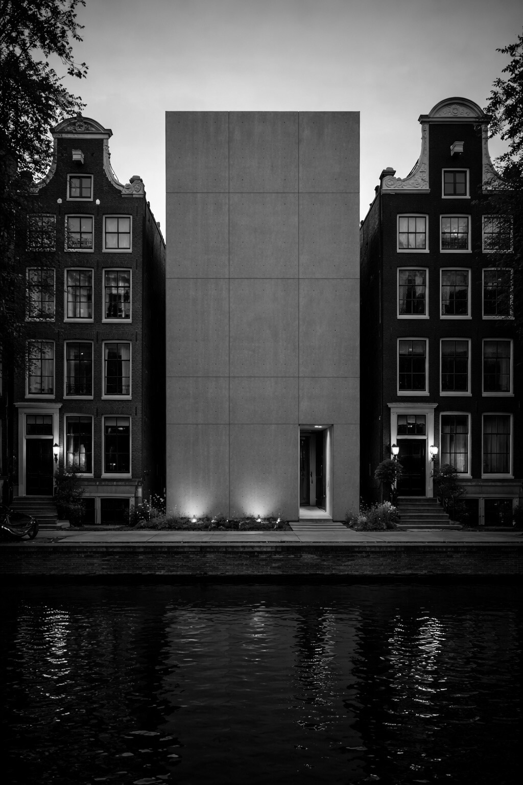 A featureless concrete monolith between two traditional Amsterdam canal houses. No highlights were harmed.
